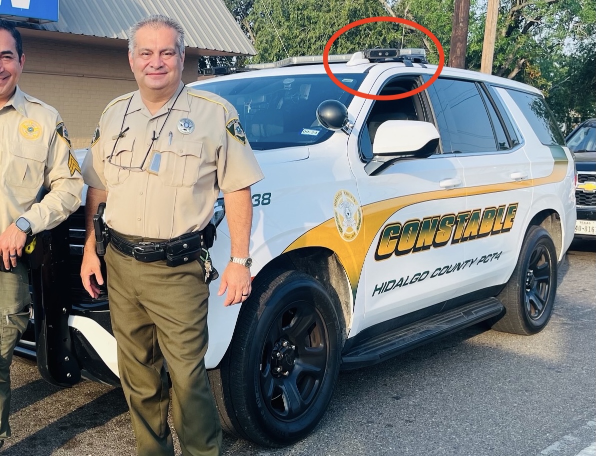 An officer stands beside patrol car. Red circle identifies mobile ALPR